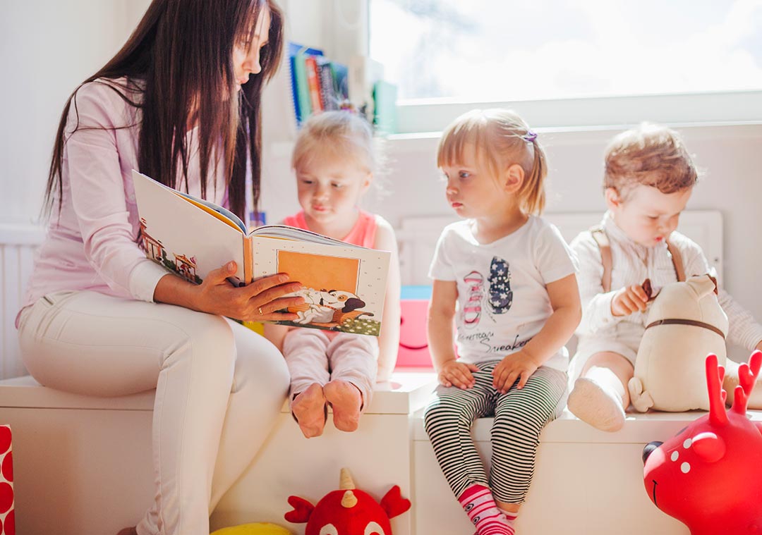 A woman applying ABA therapy techniques while reading to two children