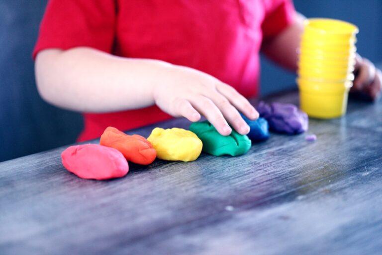 Child playing with colorful modeling clay at a table