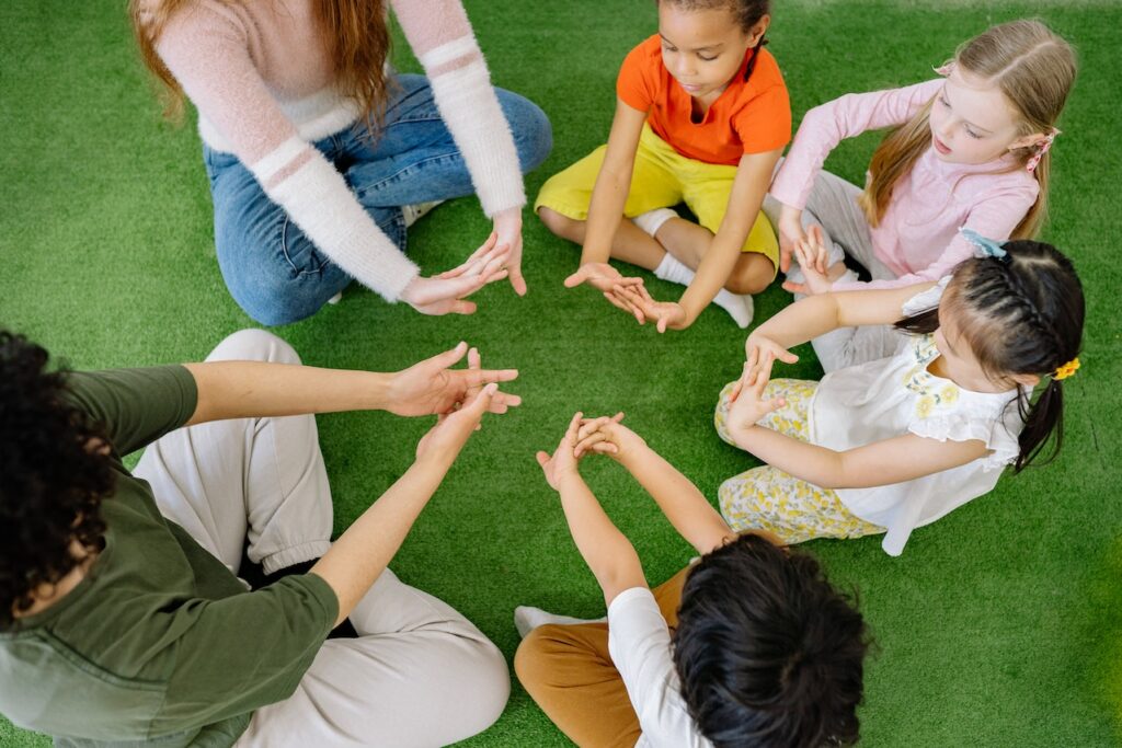 Young children sitting in a circle on the floor playing a group game