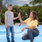 Therapist high-fiving a child during an outdoor ABA therapy session