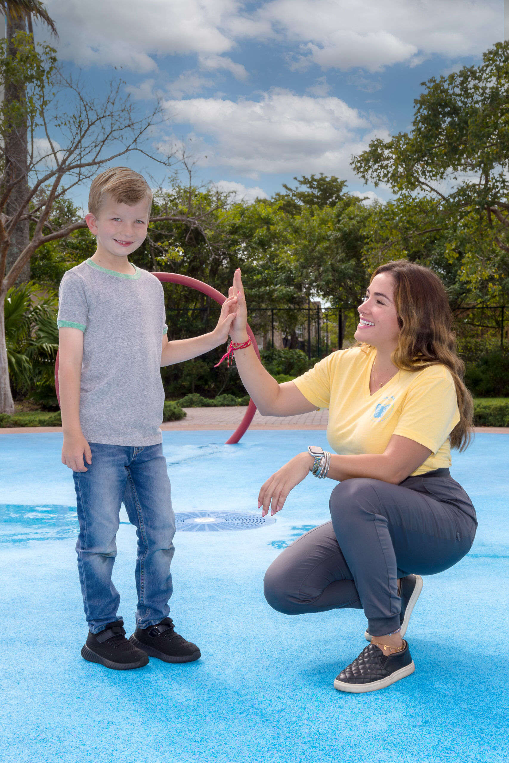 Therapist high-fiving a child during an outdoor ABA therapy session