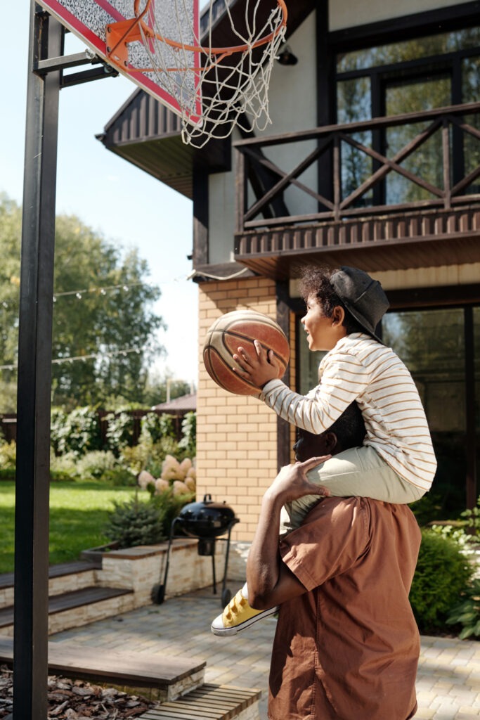 Father playing basketball outdoors with his young son