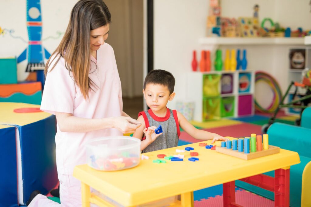 Therapist working with a young boy on a learning activity at a table
