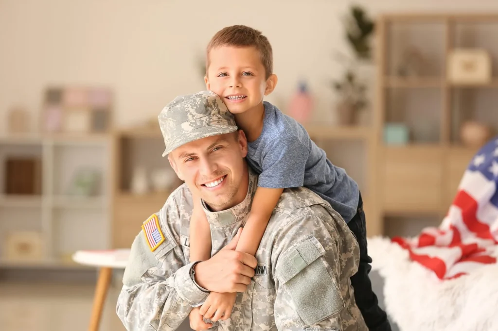 Father in a military uniform giving his smiling son a piggyback ride at home