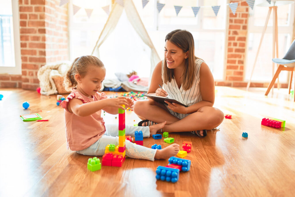 Therapist and toddler building with blocks during an in-home ABA session